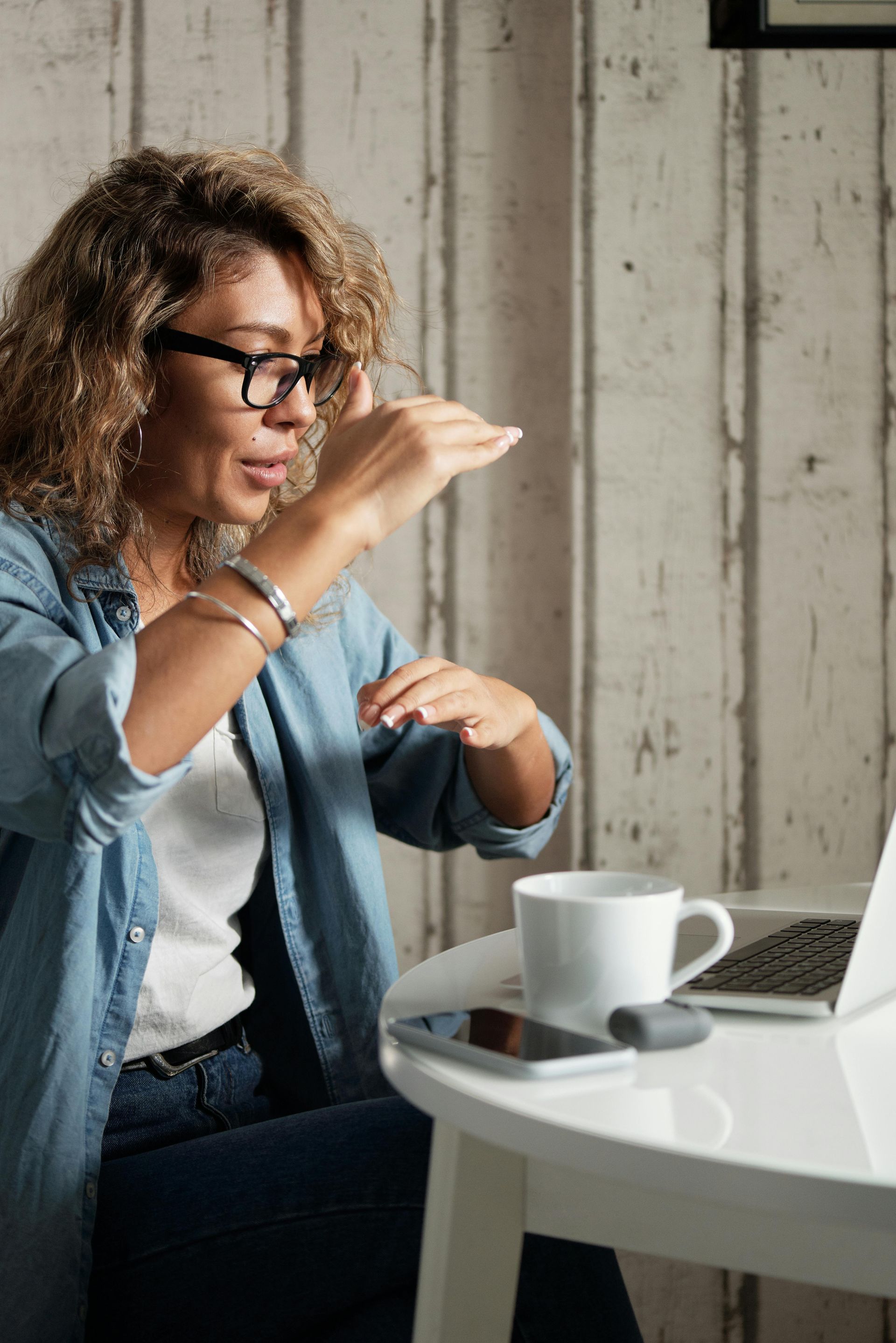 A woman is sitting at a table using a laptop computer.