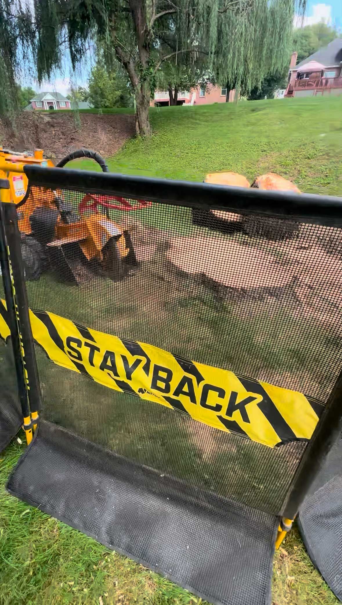 A trampoline with a stay back sign on it is sitting in the grass.