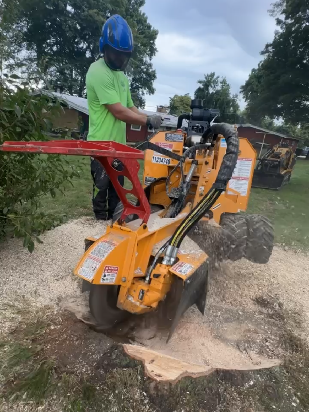 A man is using a stump grinder to remove a tree stump.