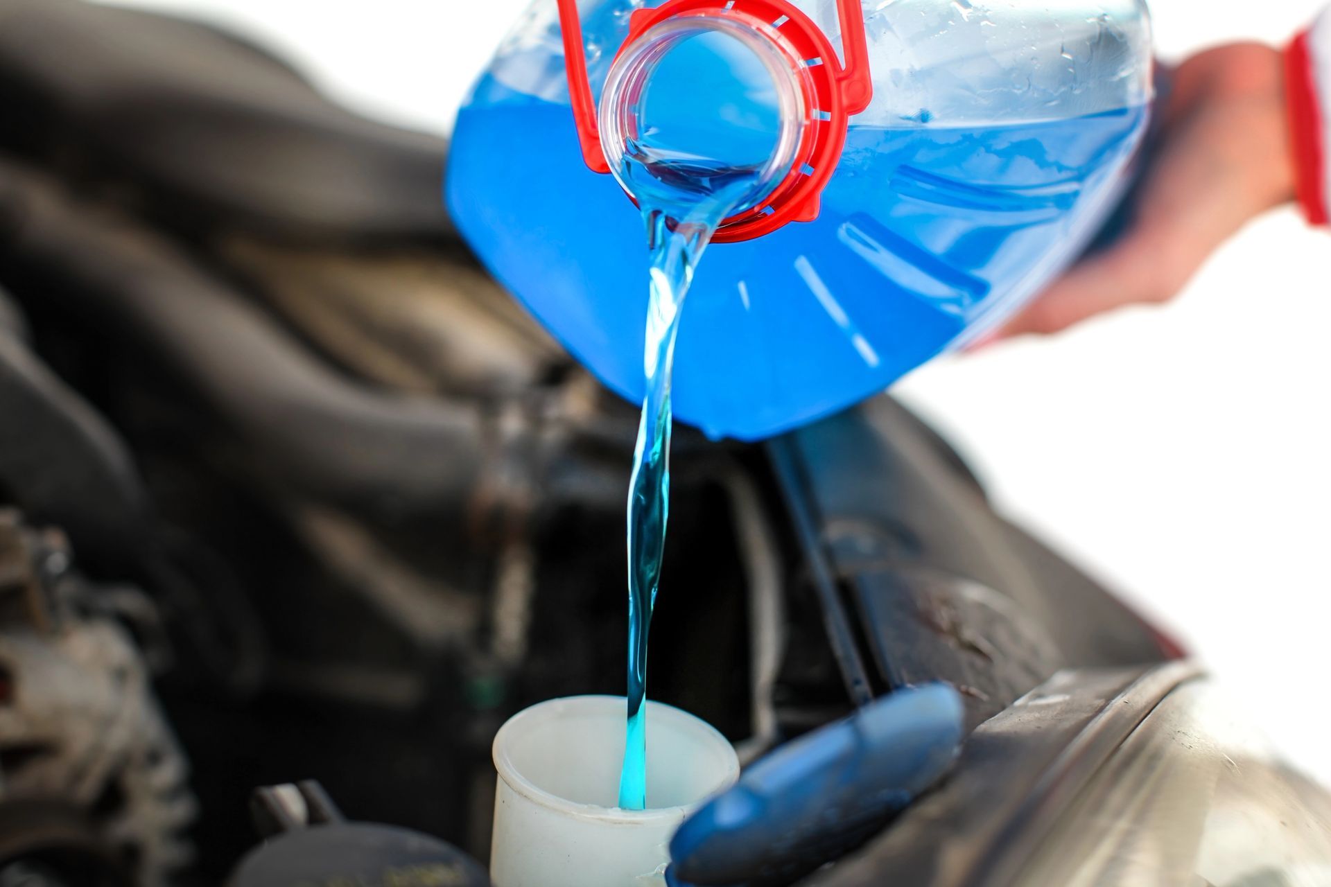 A person is pouring blue liquid into a cup