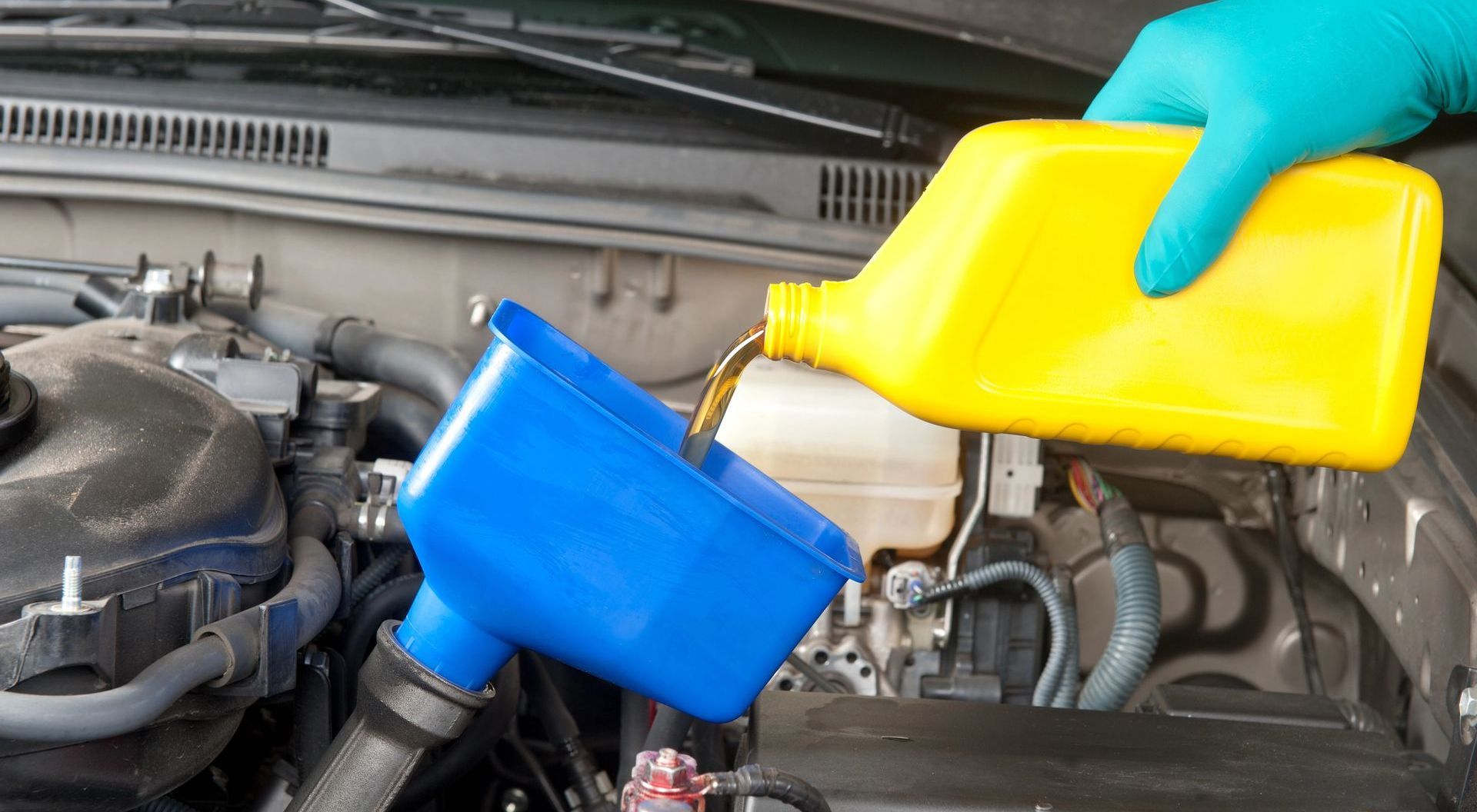 A person is pouring oil into a car engine.