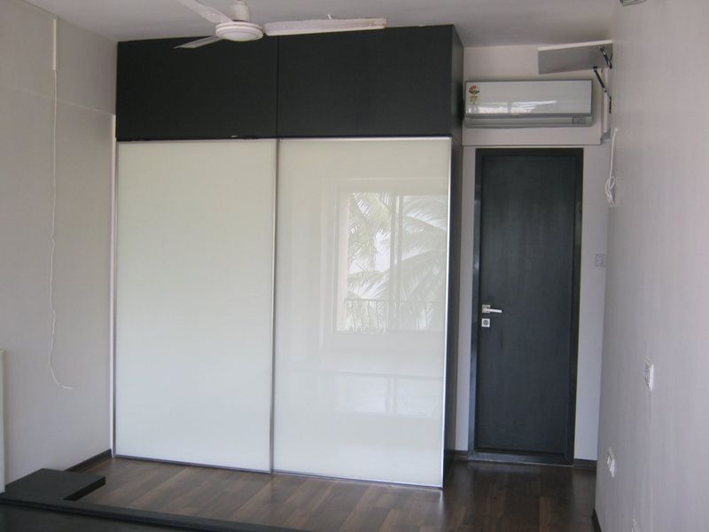 Modern bedroom with black and white sliding door closet, dark wood floor, and a dark door.