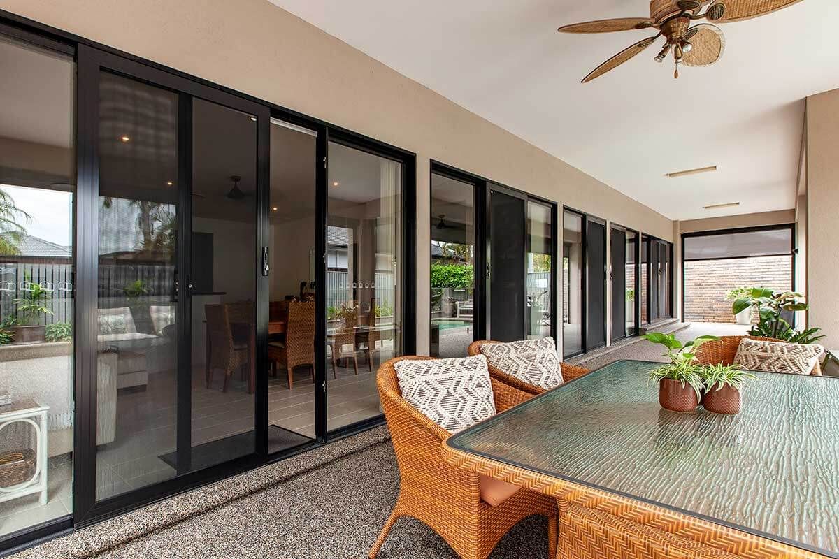 Patio with glass sliding doors, wicker furniture, and potted plants.