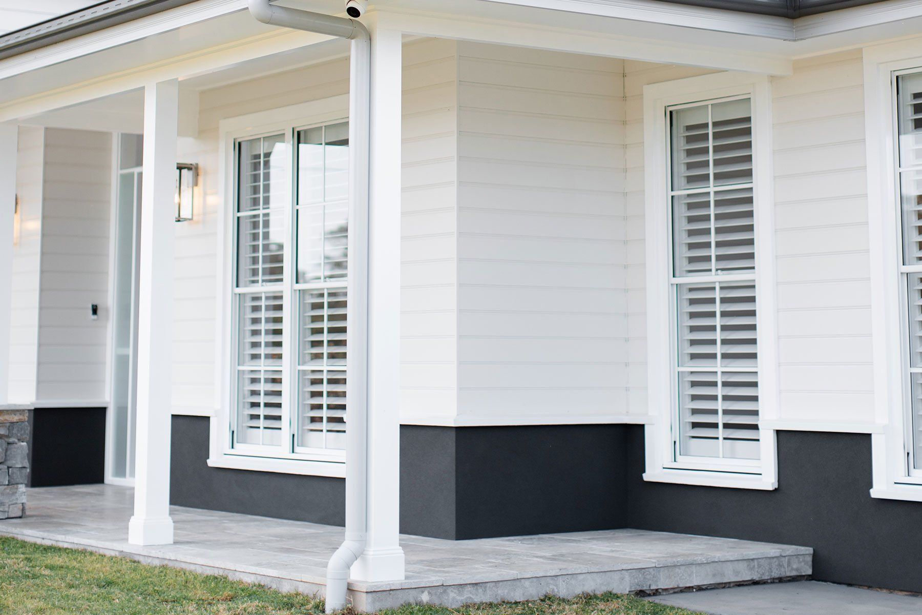 White house exterior with dark gray base, white trim, shutters, and porch.