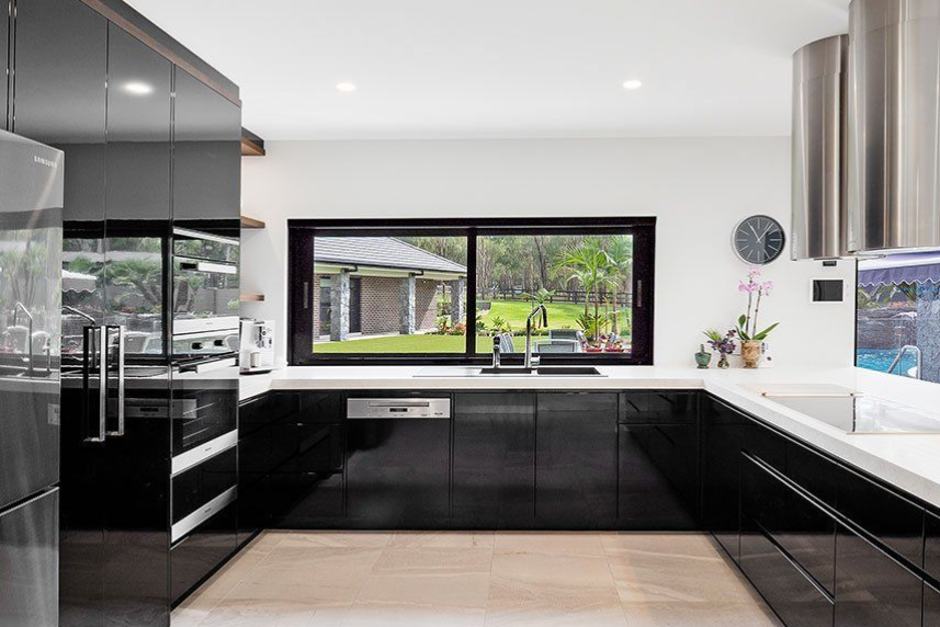 Modern black and white kitchen with a window overlooking a yard.