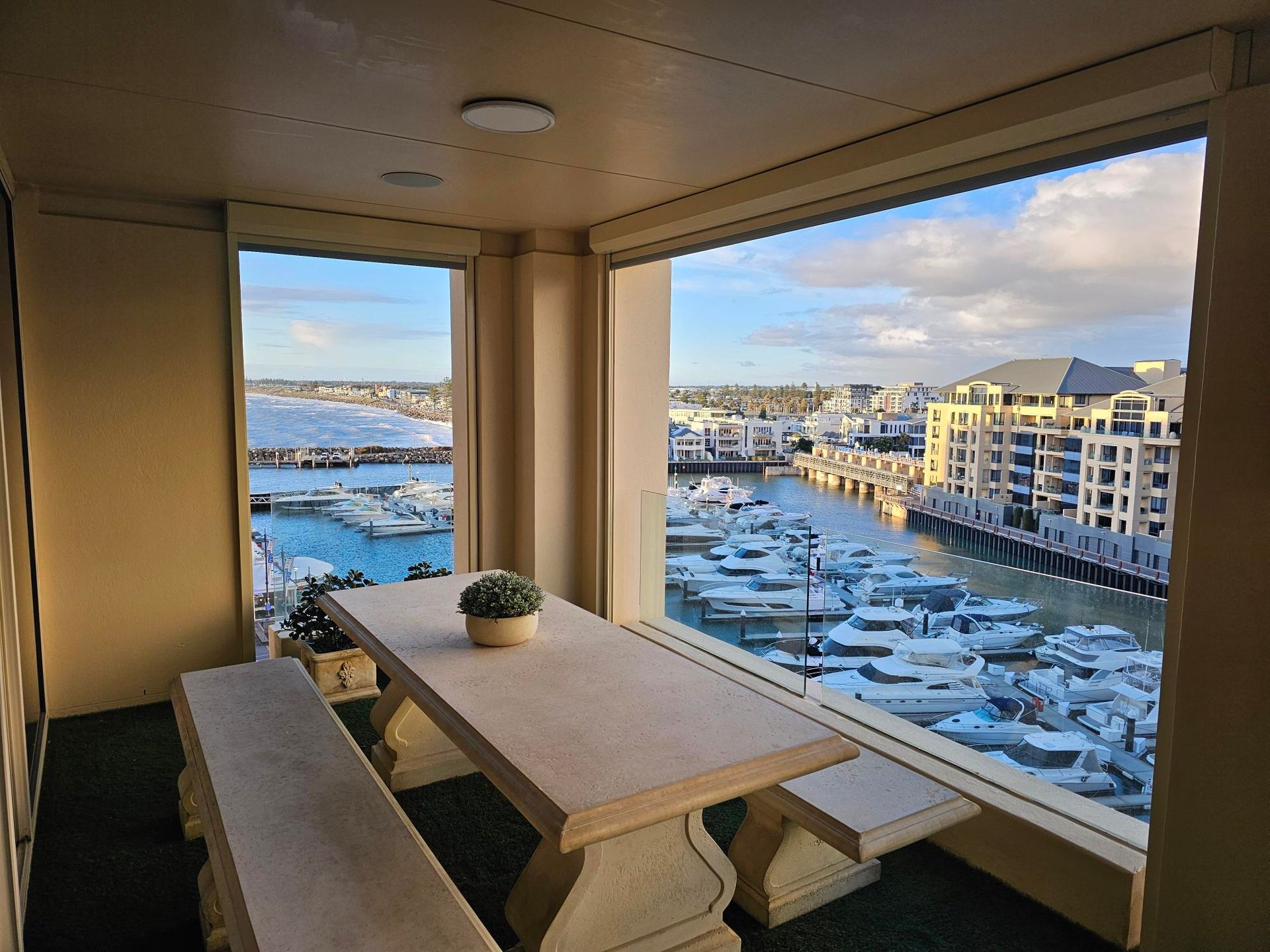 Open glass doors lead to an outdoor patio with green grass and a shade sail.