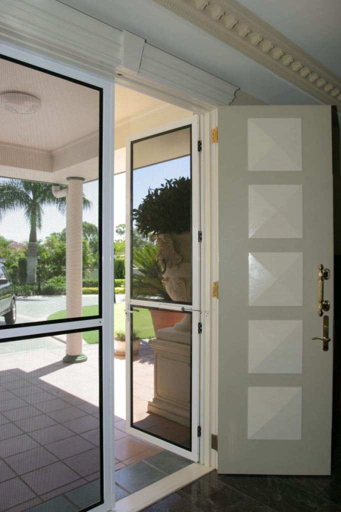 Open front door with glass screen door, white trim, leads to patio with trees.