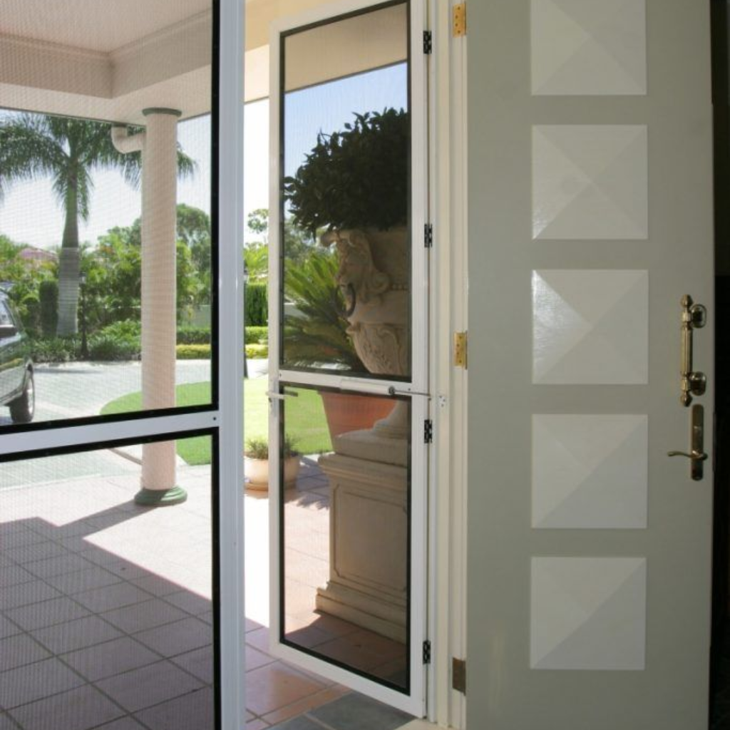 Open screen door with view of patio, and front door with square decorations.