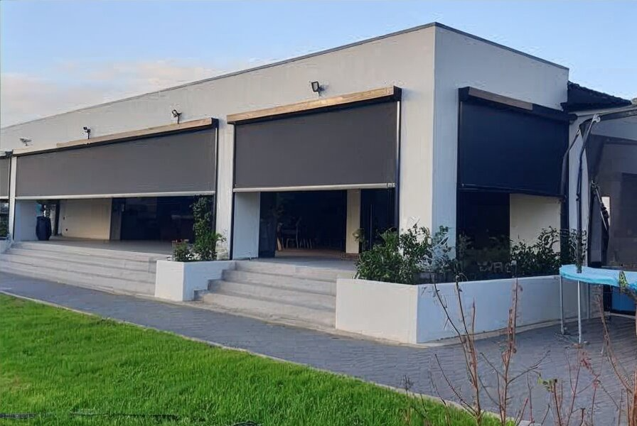 Open glass doors lead to an outdoor patio with green grass and a shade sail.