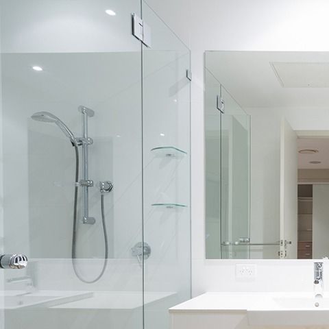 Modern white bathroom with double sink vanity, large mirror, and glass shower enclosure.