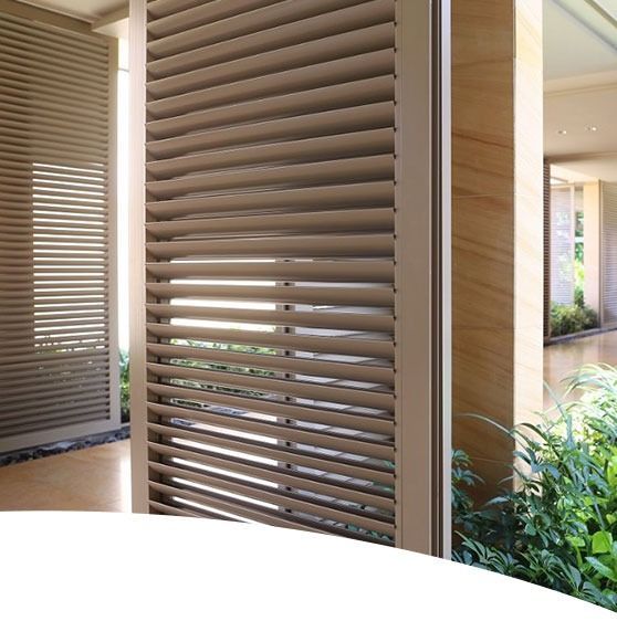 Beige slatted window or screen on a building's exterior, with natural light and plants visible.