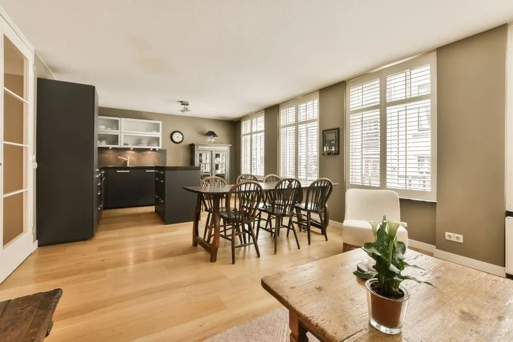 Open-plan kitchen and dining area with hardwood floors, black cabinetry, and a wooden table.