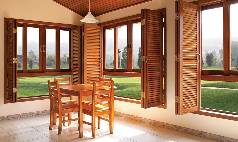 Gray and beige house exterior with front door and shuttered windows. Wooden beam and porch.