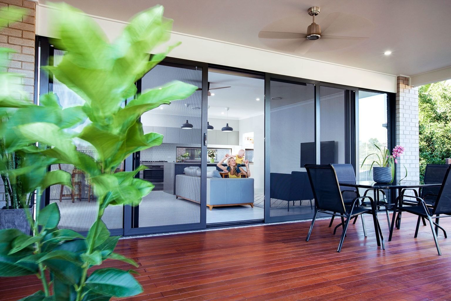 Dining room with glass table, modern chairs, and large window overlooking a yard.