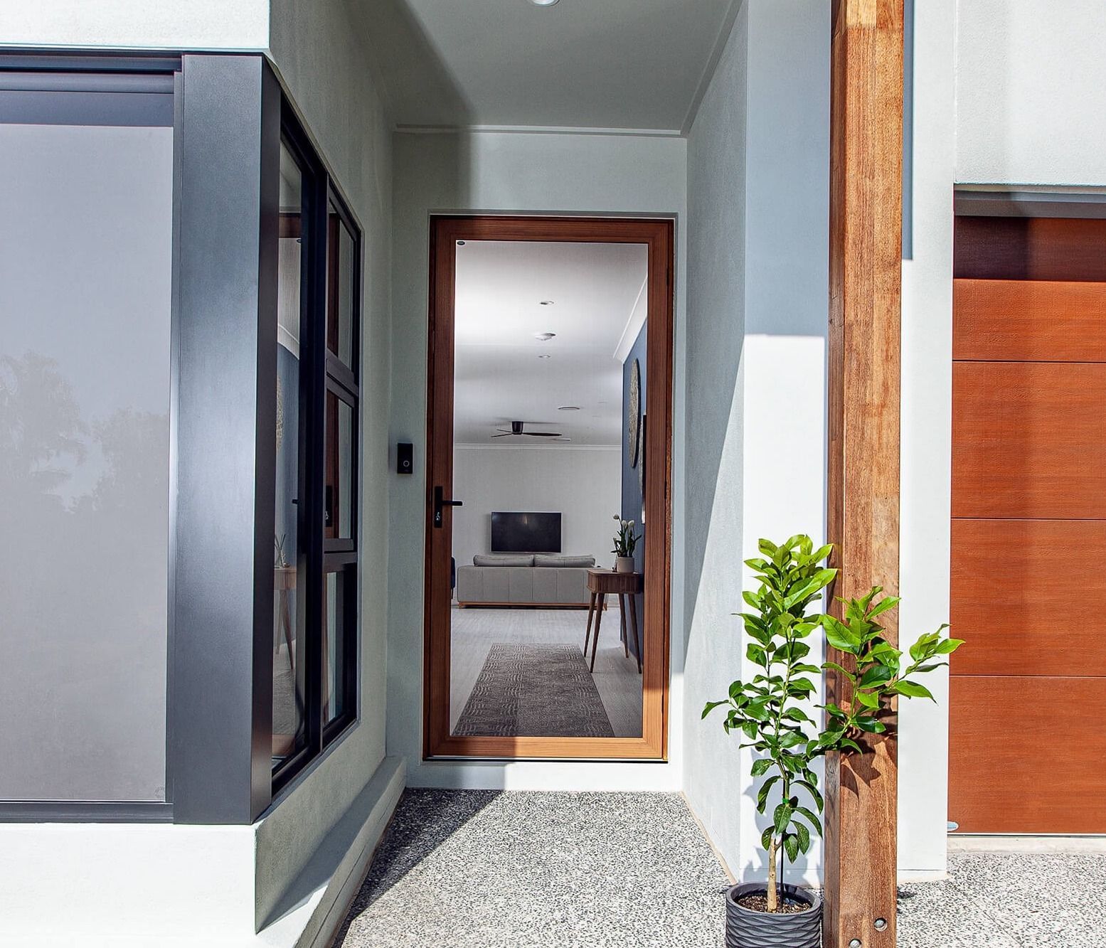 A silver door with a security screen door, standing ajar in a brick doorway.