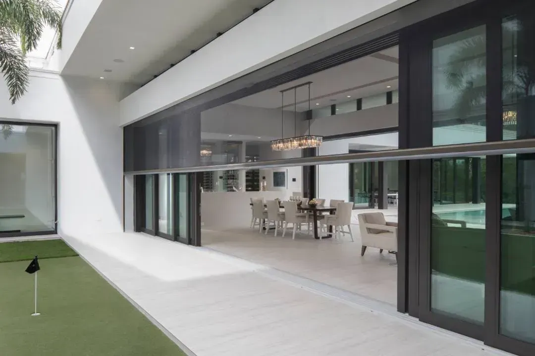 A worker installs a window frame indoors. He's wearing a tool belt and looking up at the frame.