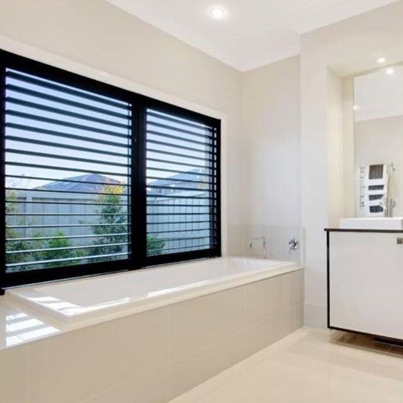 Brick exterior of a house with windows and installed roll-down shutters. A ladder and equipment are on the right.