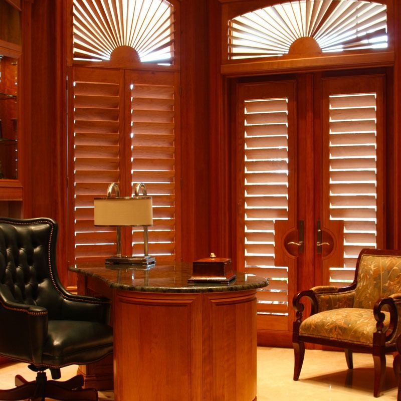 Woman pulling down a cord to operate a window blind. Sunlight streams through.