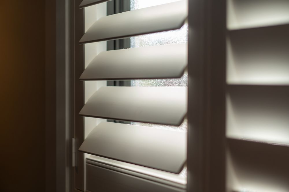 White window shutters, partially open, letting in light.