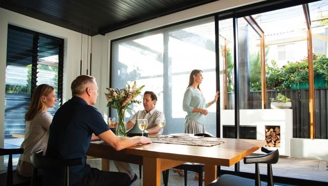 Open glass doors lead to an outdoor patio with green grass and a shade sail.