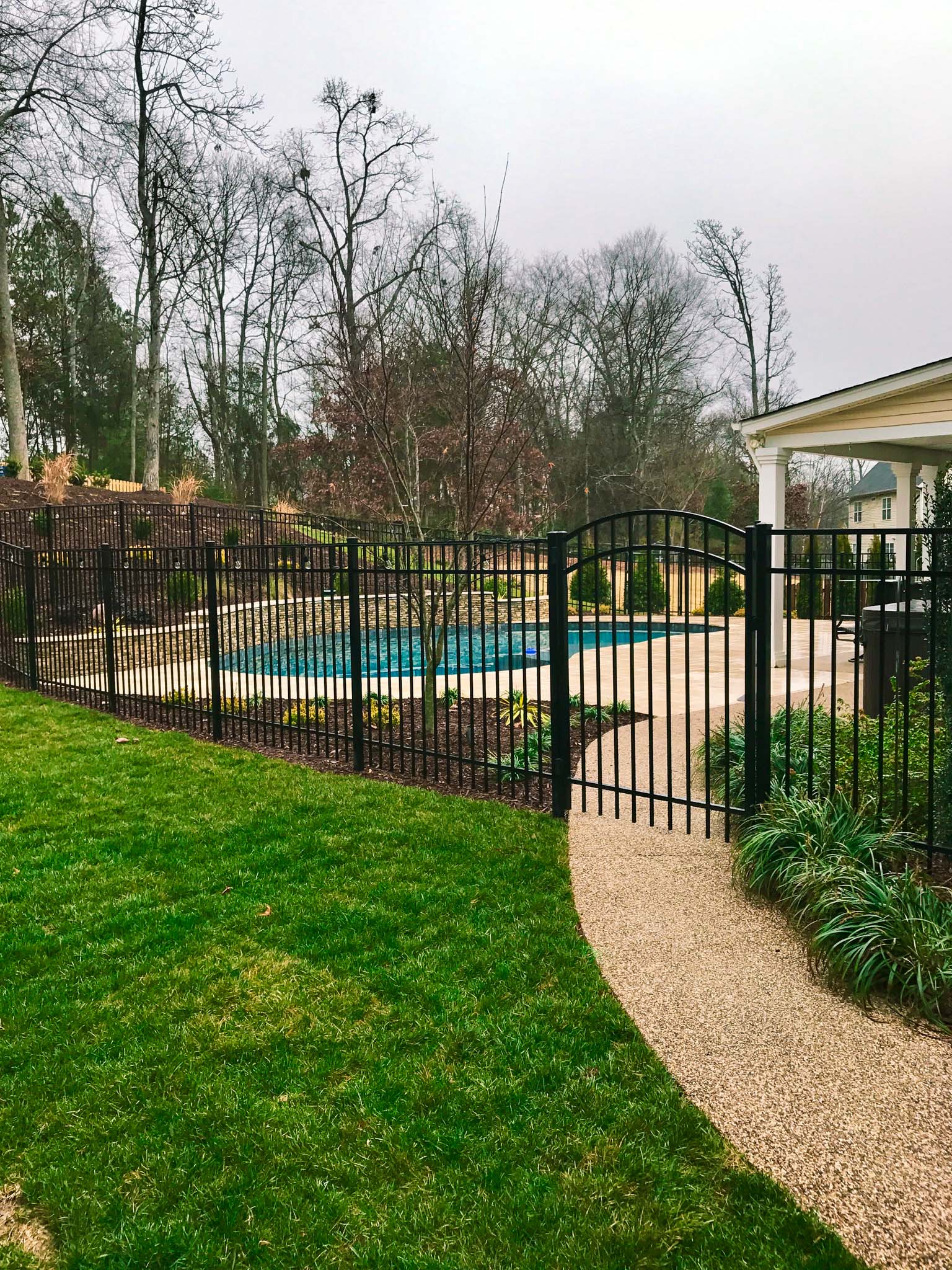 Black aluminum fence enclosing a backyard with a pool.