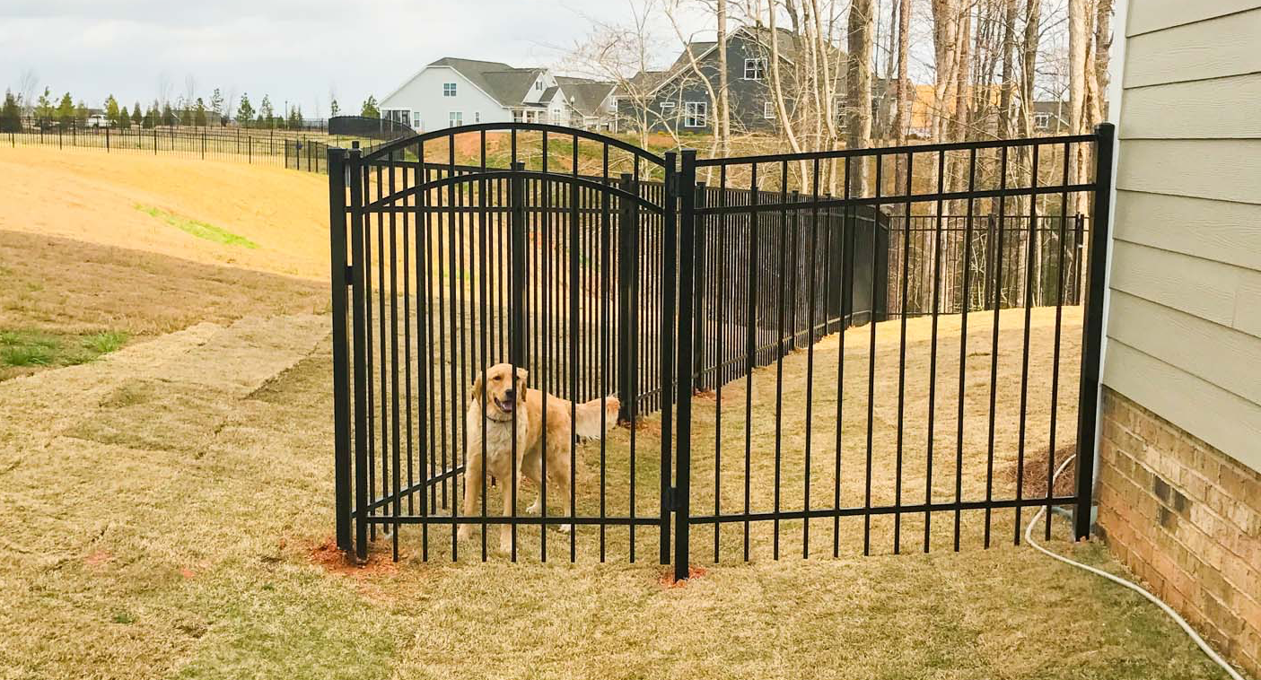 Stone and wrought iron fence combination along a driveway.