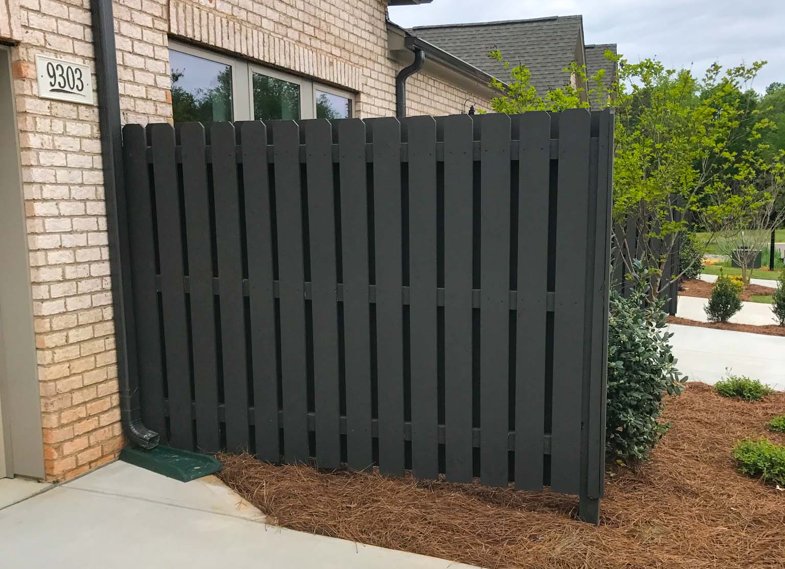 Custom wooden fence with decorative lattice top in a backyard.