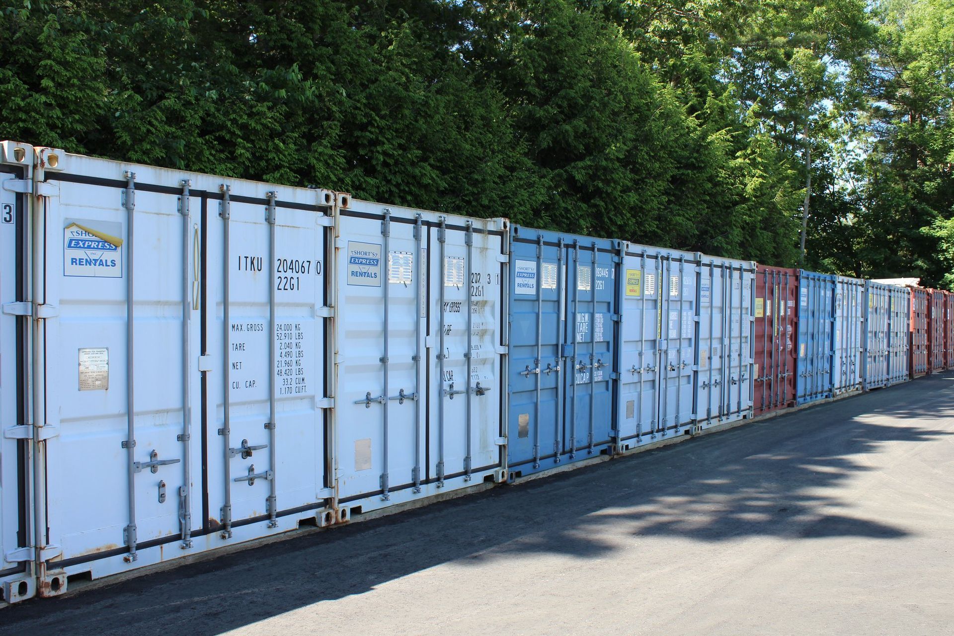 A row of shipping containers are lined up in a parking lot