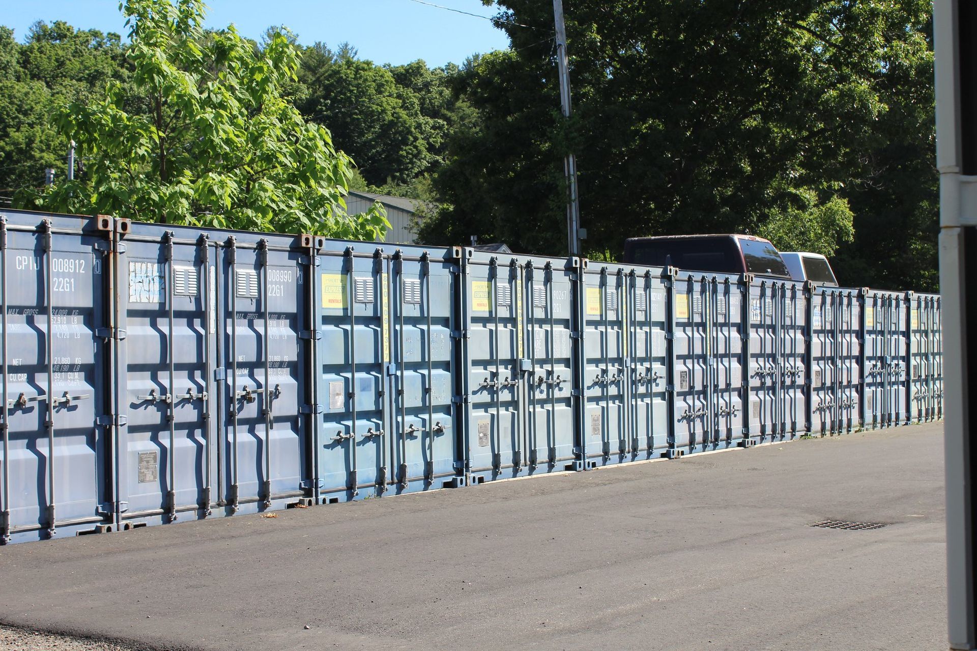A row of shipping containers are lined up on the side of the road