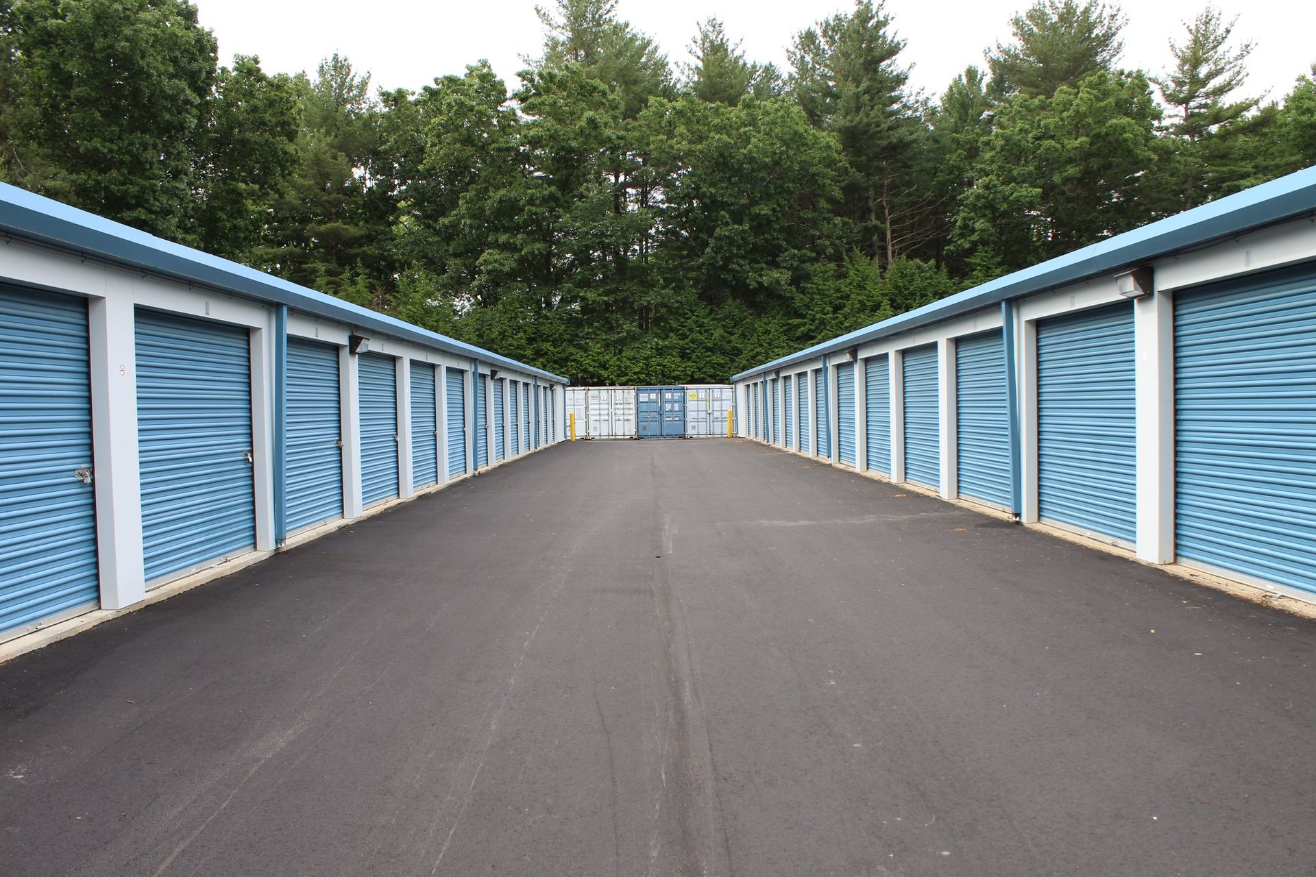 A row of blue and white storage units are lined up on the side of a road.
