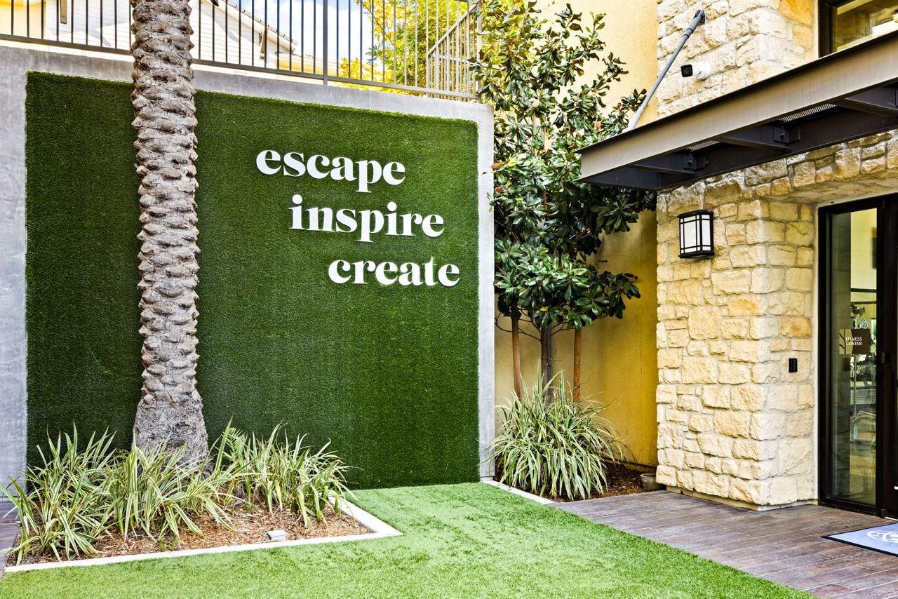 Exterior entrance featuring a green turf wall with large white text sign.
