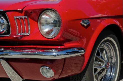 A red mustang is parked on the side of the road