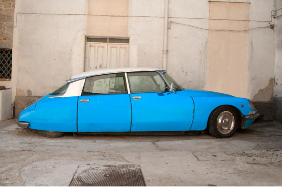 A blue and white car is parked in front of a building