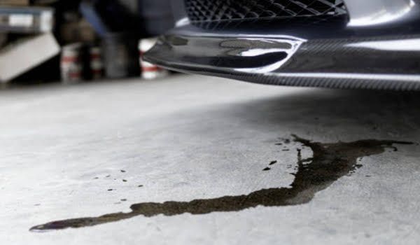 A car is leaking oil on the ground in a garage.