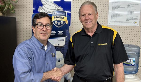 Two men shaking hands in front of a sign that says michelin