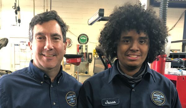 Two men are standing next to each other in a garage.