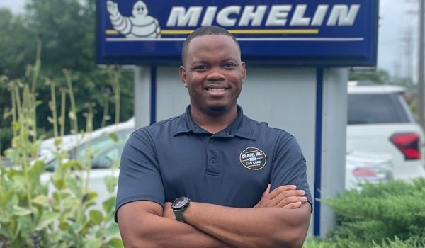 A man is standing in front of a michelin sign.