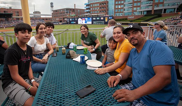 A group of people sitting at a picnic table at a baseball game