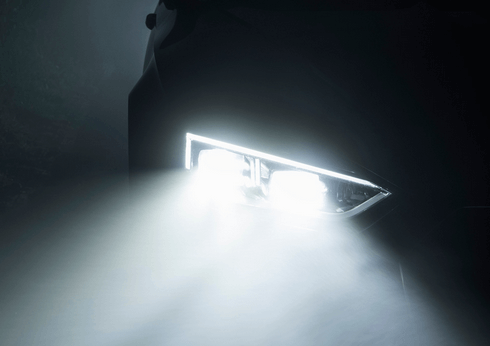 A car headlight is shining brightly in the dark.