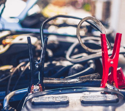A close up of a car battery with jumper cables attached to it