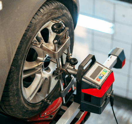 A car wheel is being adjusted by a machine in a garage.