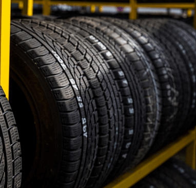A row of tires are lined up on a yellow rack