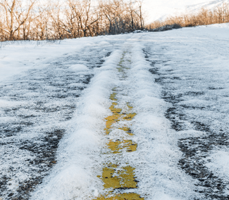 A snowy road with a yellow line in the middle