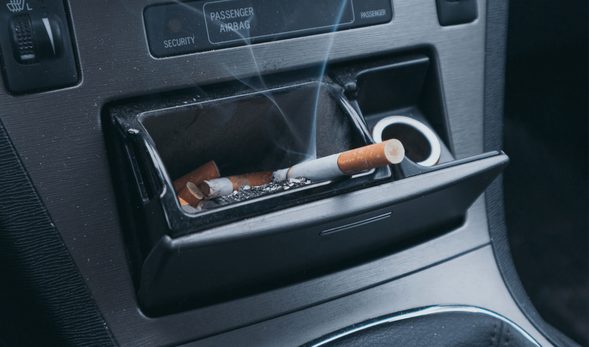 A car ashtray with cigarettes and a lighter in it