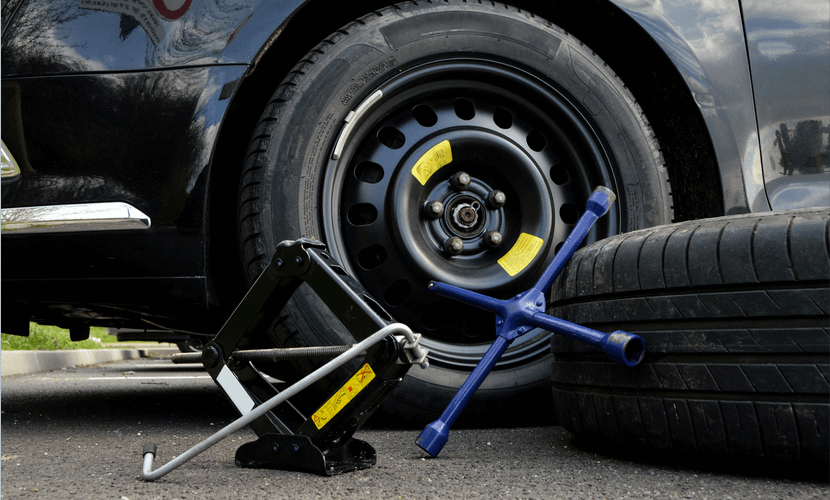 A car is being changed with a jack and a tire wrench