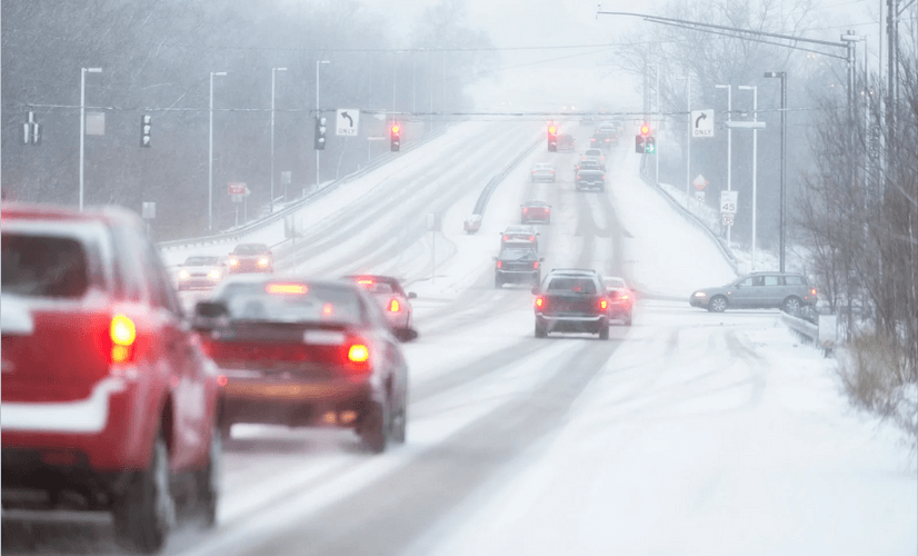 A bunch of cars are driving down a snowy road.