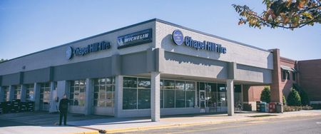 Exterior of a Pearle Vision store. The building is gray with blue signage. A person stands outside.