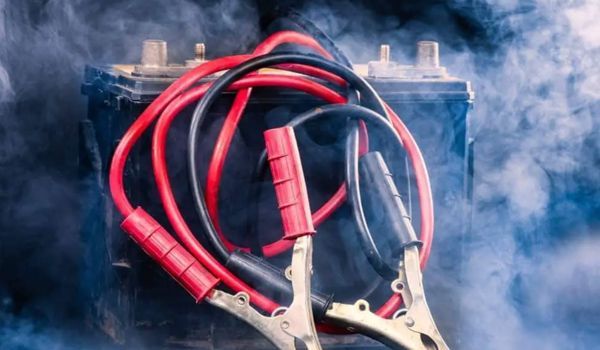 A close up of a battery with a pair of jumper cables attached to it.