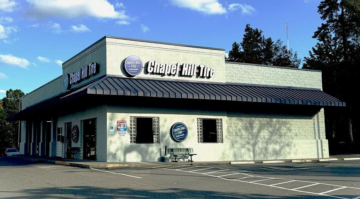 Chapel Hill Tire building with blue and white signage under a blue sky.