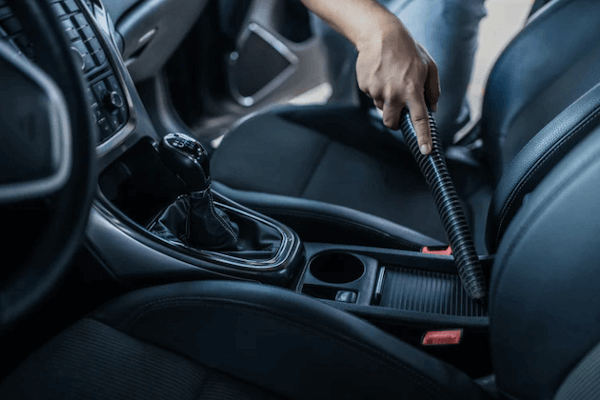 A person is cleaning the interior of a car with a vacuum cleaner.